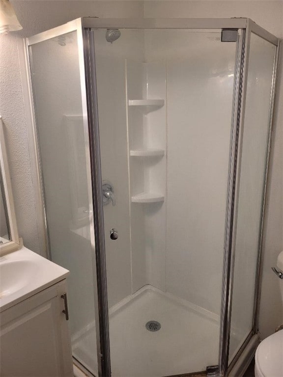 bathroom with toilet, vanity, and walk in shower