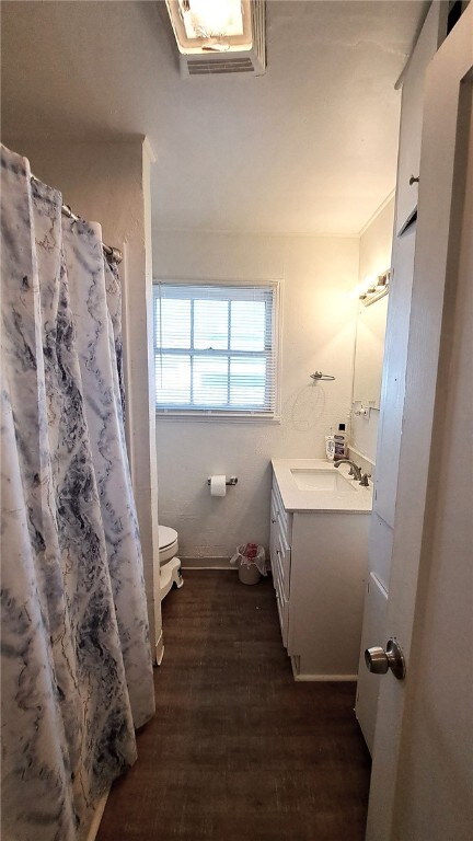 full bathroom with a shower with shower curtain, vanity, toilet, and wood finished floors