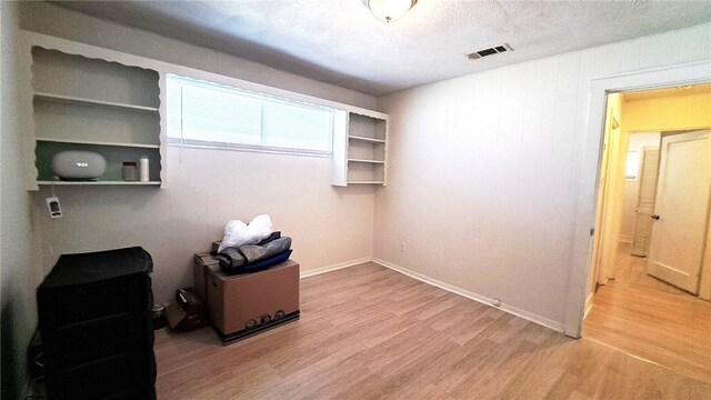 interior space with light wood finished floors, visible vents, and a textured ceiling