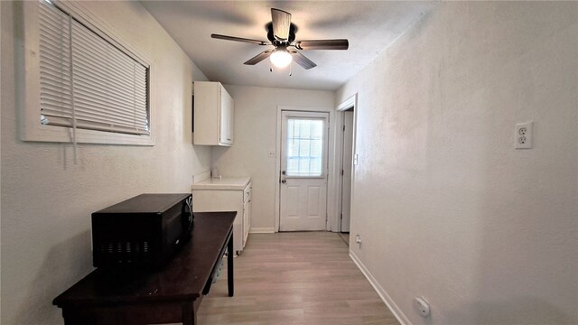 interior space featuring light wood-style floors, ceiling fan, and baseboards