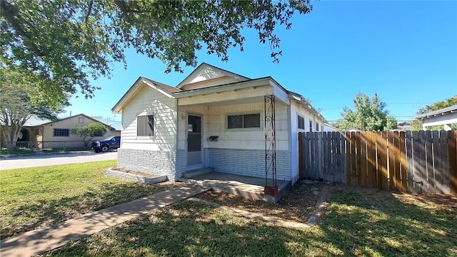 view of front of house with brick siding, fence, and a front lawn