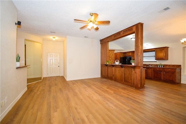 unfurnished living room featuring light wood-type flooring, a textured ceiling, and ceiling fan