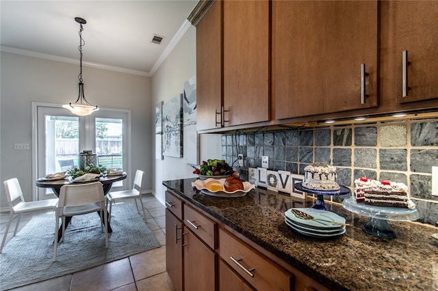 kitchen featuring dark tile patterned flooring, ornamental molding, backsplash, pendant lighting, and dark stone countertops