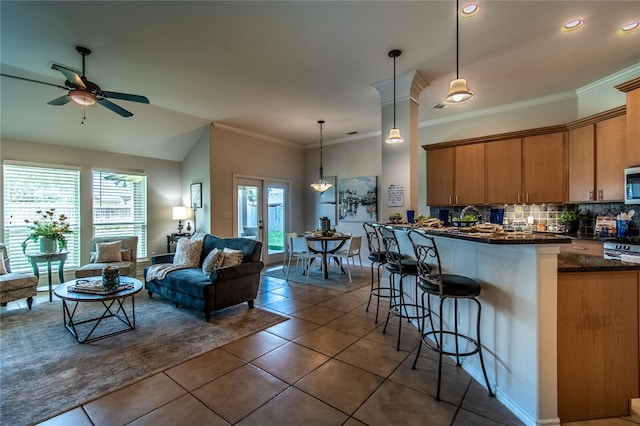 kitchen featuring a wealth of natural light, hanging light fixtures, ceiling fan, and a breakfast bar