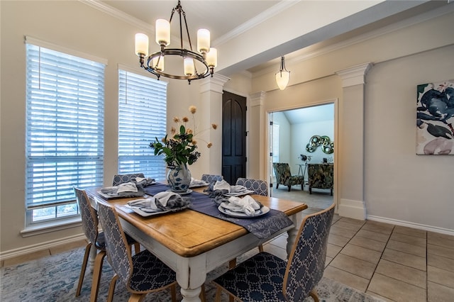 dining area featuring tile patterned flooring, a chandelier, crown molding, and decorative columns