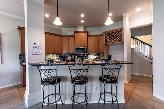 kitchen with pendant lighting, kitchen peninsula, decorative backsplash, and a kitchen bar