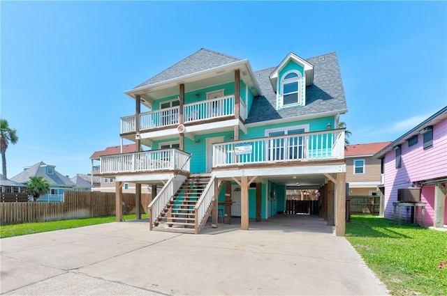 616 Sandcastle Dr, Port Aransas, TX 78373 - coastal inspired home with a carport, a balcony, roof with shingles, concrete driveway, and stairs