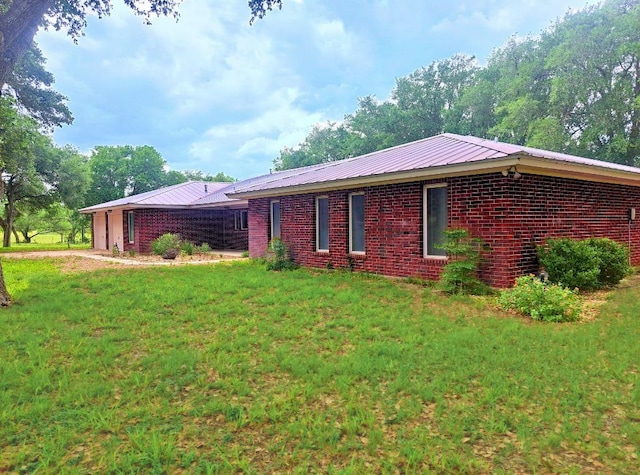 112 Fm 1042, Three Rivers, TX 78071 - view of home's exterior featuring brick siding, a lawn, a metal roof, and an attached garage