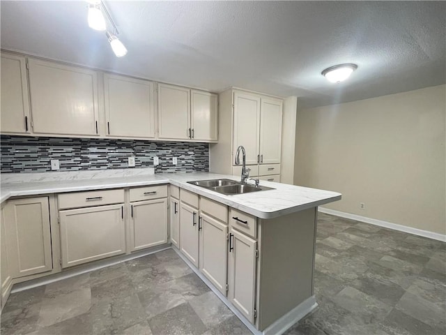 kitchen with sink, tasteful backsplash, white cabinets, a textured ceiling, and kitchen peninsula