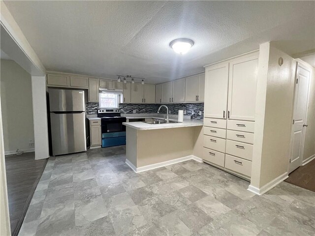 kitchen featuring appliances with stainless steel finishes, kitchen peninsula, sink, and decorative backsplash