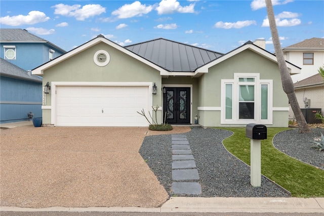 single story home featuring stucco siding, an attached garage, a standing seam roof, french doors, and concrete driveway