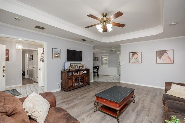 537 Vista Dr, Odem, TX 78370 - living room featuring ceiling fan, a tray ceiling, ornamental molding, wood finished floors, and baseboards
