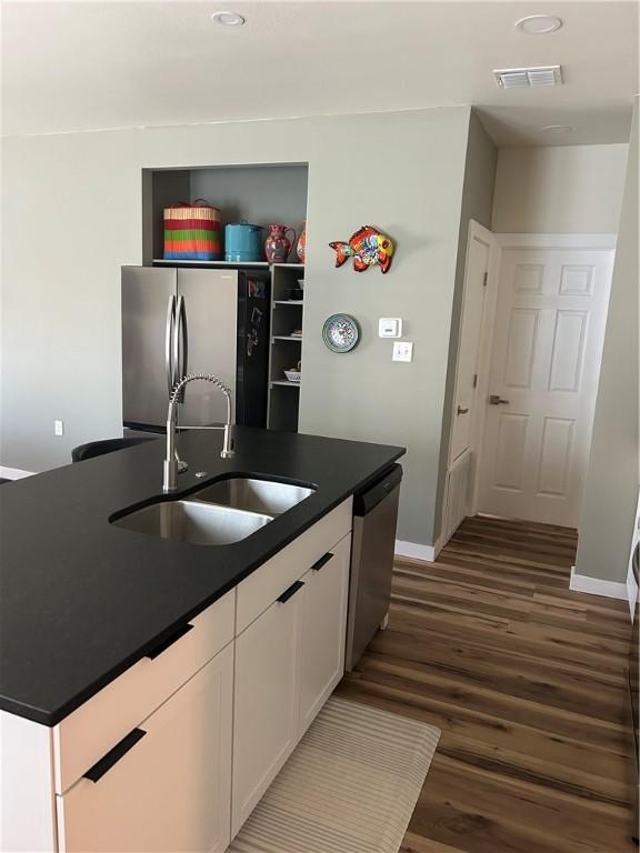 kitchen with visible vents, a sink, dark countertops, appliances with stainless steel finishes, and white cabinets