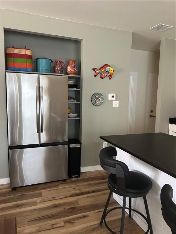 kitchen featuring visible vents, freestanding refrigerator, baseboards, and wood finished floors