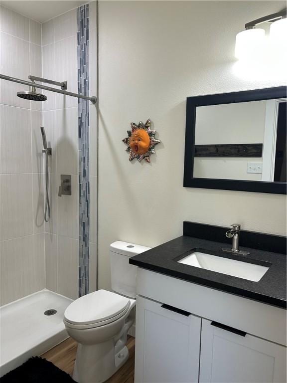 full bath featuring vanity, a shower stall, toilet, and wood finished floors