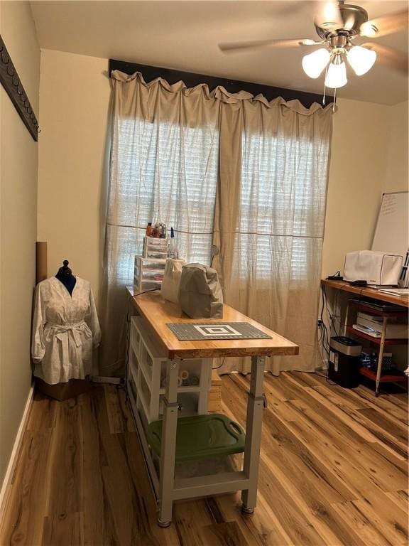 office space featuring baseboards, wood finished floors, and a ceiling fan