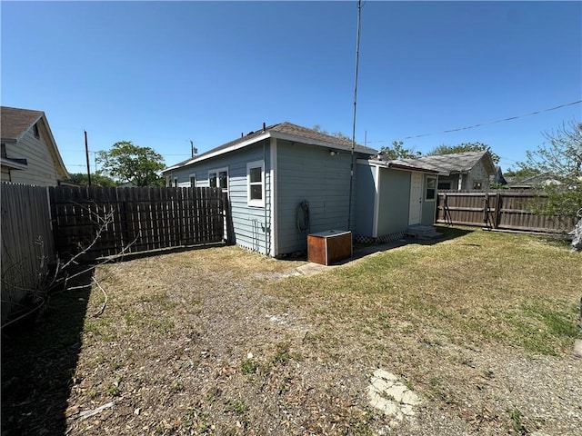rear view of house with a lawn and a fenced backyard