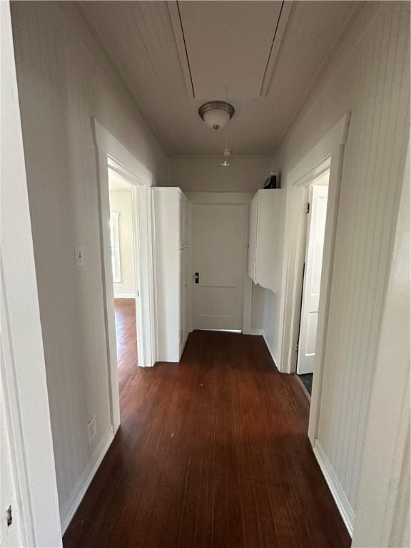hall with attic access, baseboards, and dark wood-style floors