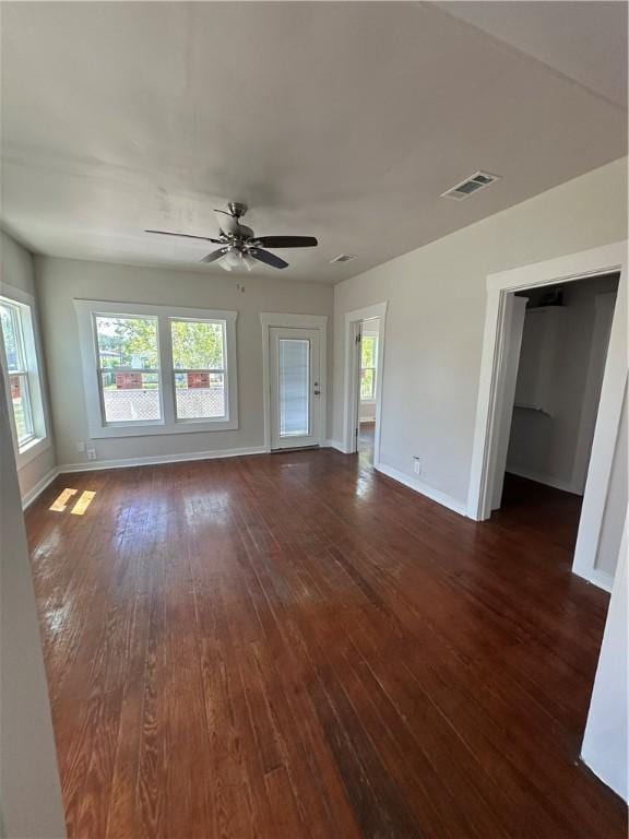 interior space featuring baseboards, a ceiling fan, visible vents, and dark wood finished floors