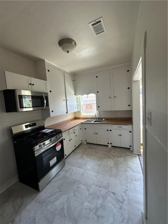 kitchen with white cabinets, visible vents, a sink, and appliances with stainless steel finishes