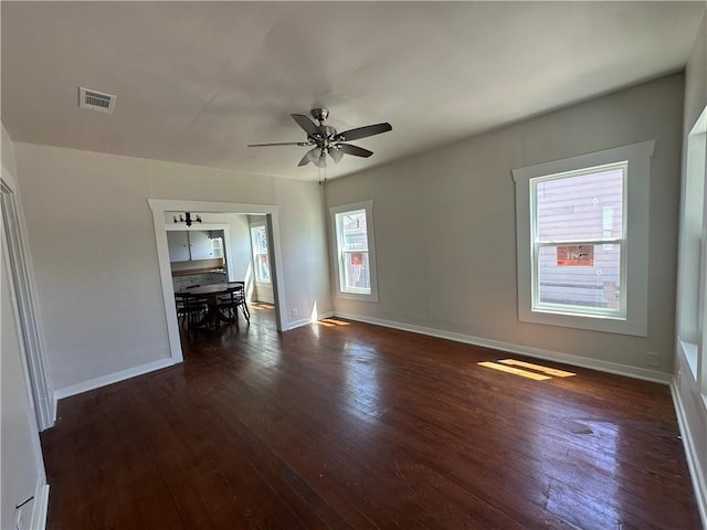 unfurnished room with ceiling fan, visible vents, baseboards, and dark wood-style flooring