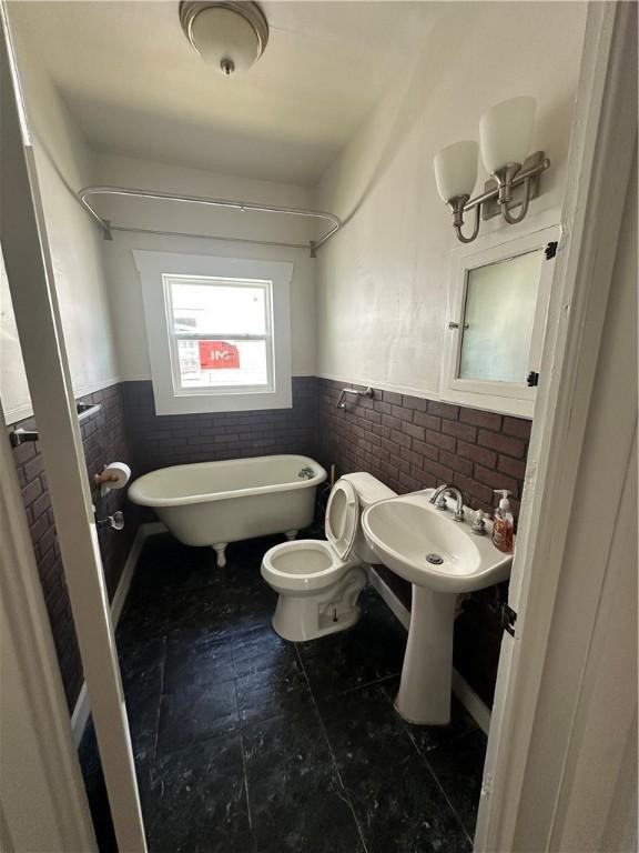 full bathroom with a soaking tub, tile patterned flooring, toilet, and wainscoting