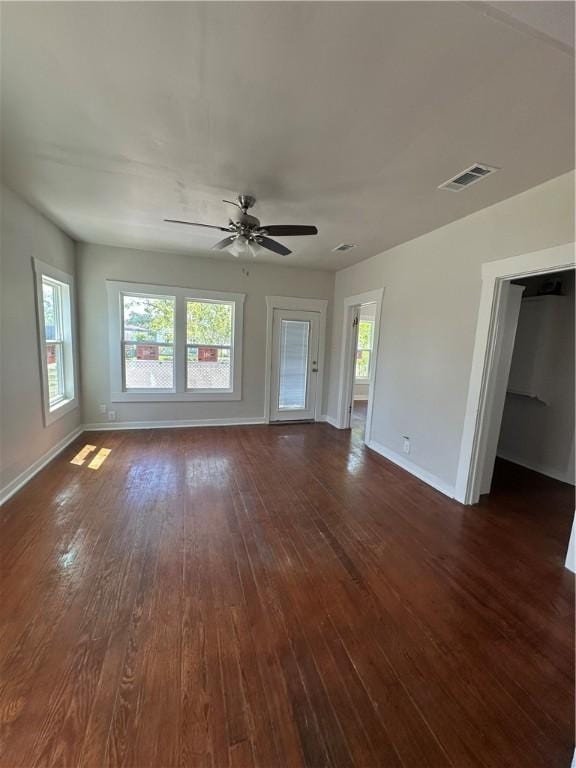 unfurnished living room featuring a ceiling fan, baseboards, visible vents, and dark wood-style floors