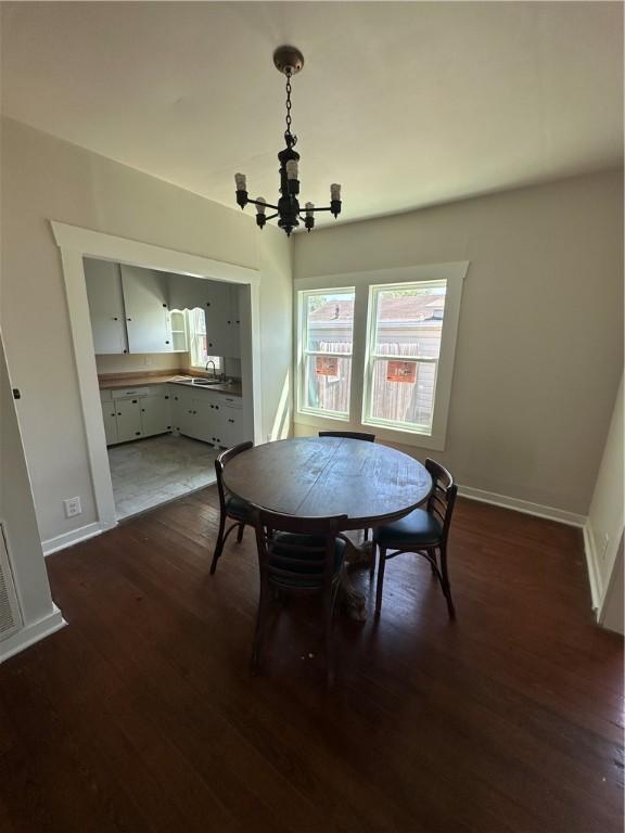 dining space featuring baseboards, an inviting chandelier, and dark wood finished floors