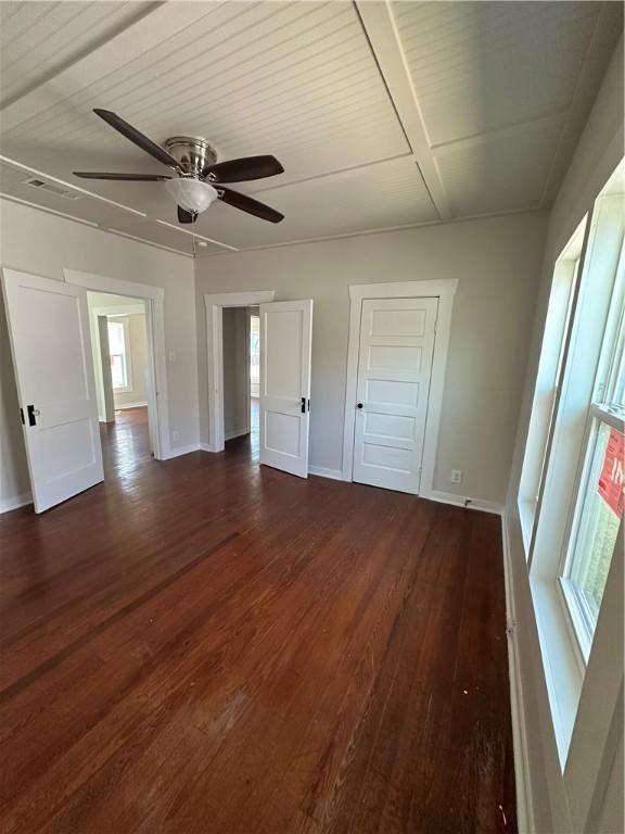 unfurnished bedroom featuring baseboards and dark wood-type flooring