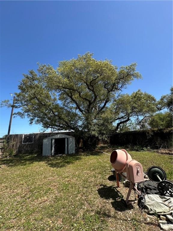 view of yard with an outdoor structure, fence, and a shed