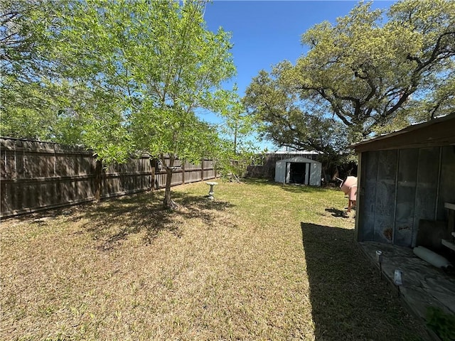 view of yard featuring a fenced backyard, an outdoor structure, and a shed