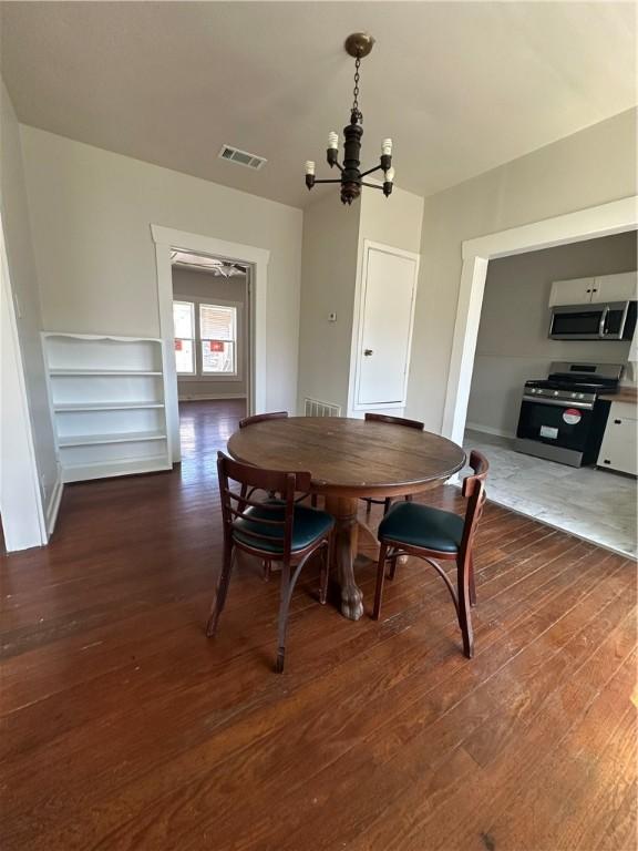 dining room featuring visible vents, wood finished floors, and an inviting chandelier
