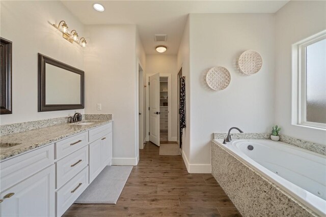 641 Hyacinth Dr, Corpus Christi, TX 78413 - bathroom with double vanity, a garden tub, wood finished floors, baseboards, and a spacious closet