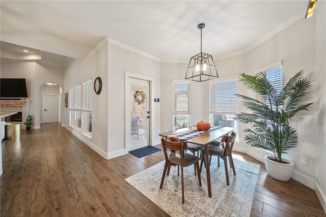 641 Hyacinth Dr, Corpus Christi, TX 78413 - dining area featuring wood-type flooring, baseboards, crown molding, arched walkways, and a fireplace