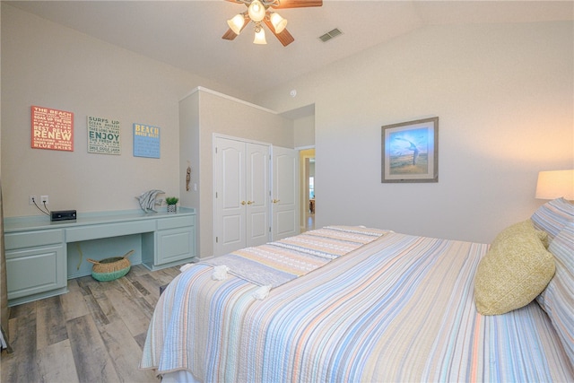 bedroom with a closet, built in desk, lofted ceiling, ceiling fan, and light hardwood / wood-style flooring