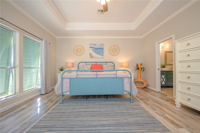 bedroom featuring a raised ceiling, light wood-type flooring, and crown molding