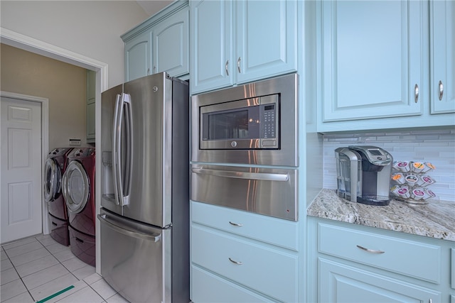 kitchen featuring white cabinets, light tile patterned floors, light stone countertops, appliances with stainless steel finishes, and independent washer and dryer