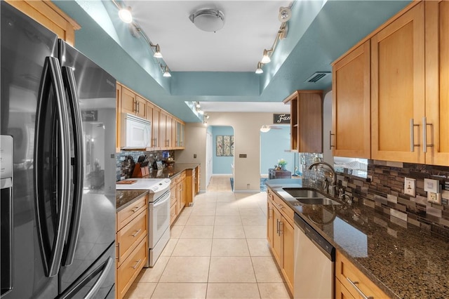 kitchen featuring tasteful backsplash, sink, light tile patterned floors, and appliances with stainless steel finishes