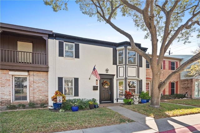 view of property featuring a balcony and a front lawn