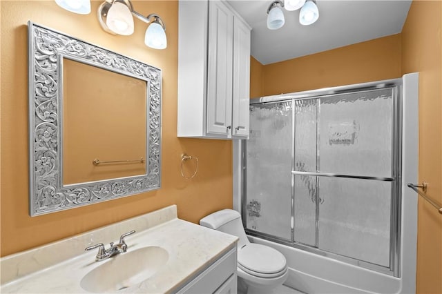 full bathroom with combined bath / shower with glass door, vanity, and toilet