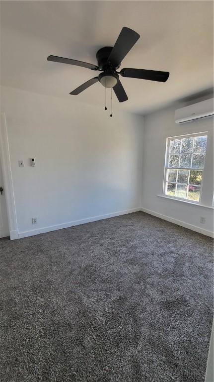 empty room with ceiling fan, dark carpet, and a wall unit AC