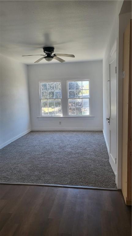 spare room with dark carpet, a wealth of natural light, and ceiling fan