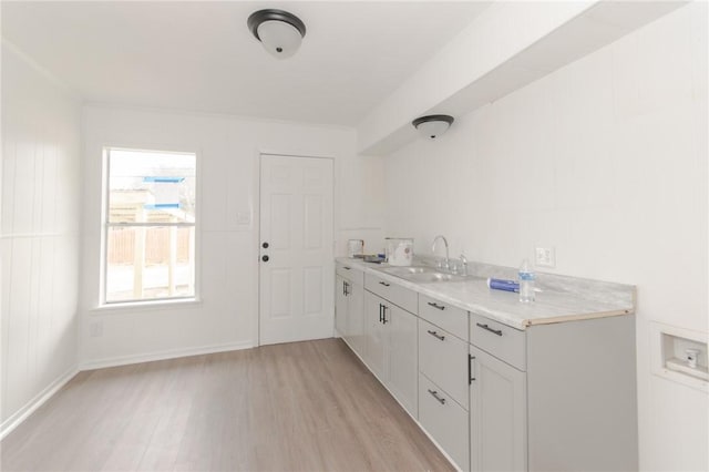 kitchen with sink, white cabinets, and light hardwood / wood-style flooring