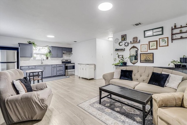 living room featuring light wood-type flooring and sink