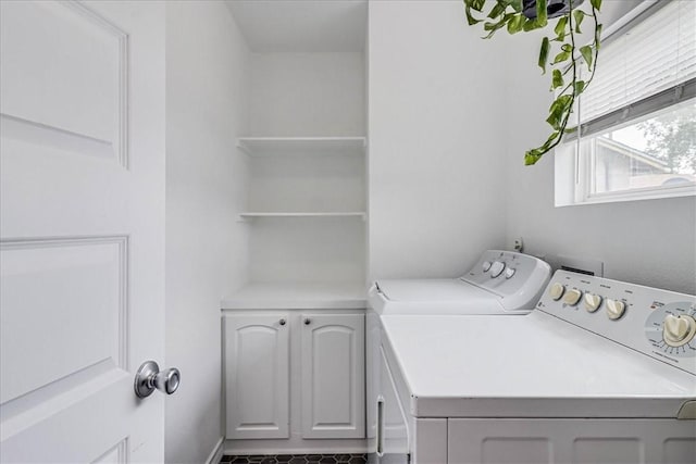 clothes washing area featuring cabinets and washer and clothes dryer