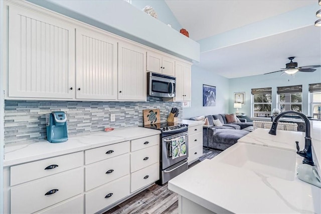 kitchen with lofted ceiling, sink, tasteful backsplash, appliances with stainless steel finishes, and ceiling fan