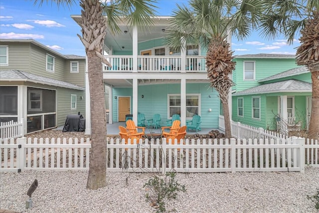 view of front of property featuring a fire pit, a balcony, a patio area, and a sunroom