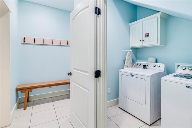 clothes washing area featuring cabinets, washer and dryer, and light tile patterned floors