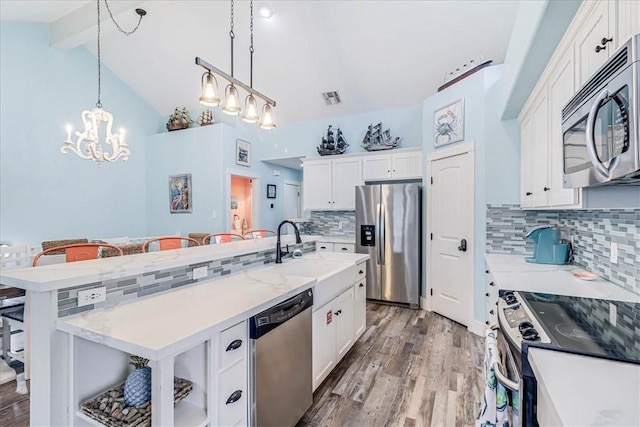 kitchen featuring stainless steel appliances, pendant lighting, white cabinets, and lofted ceiling with beams