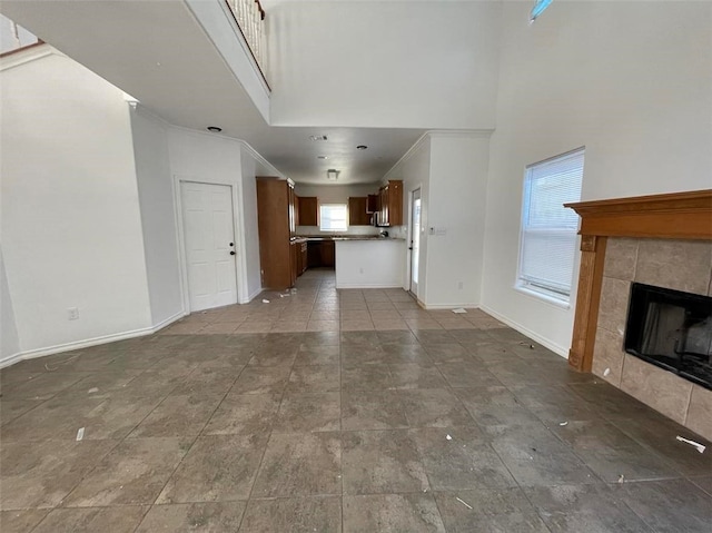 unfurnished living room with a fireplace, a high ceiling, and ornamental molding